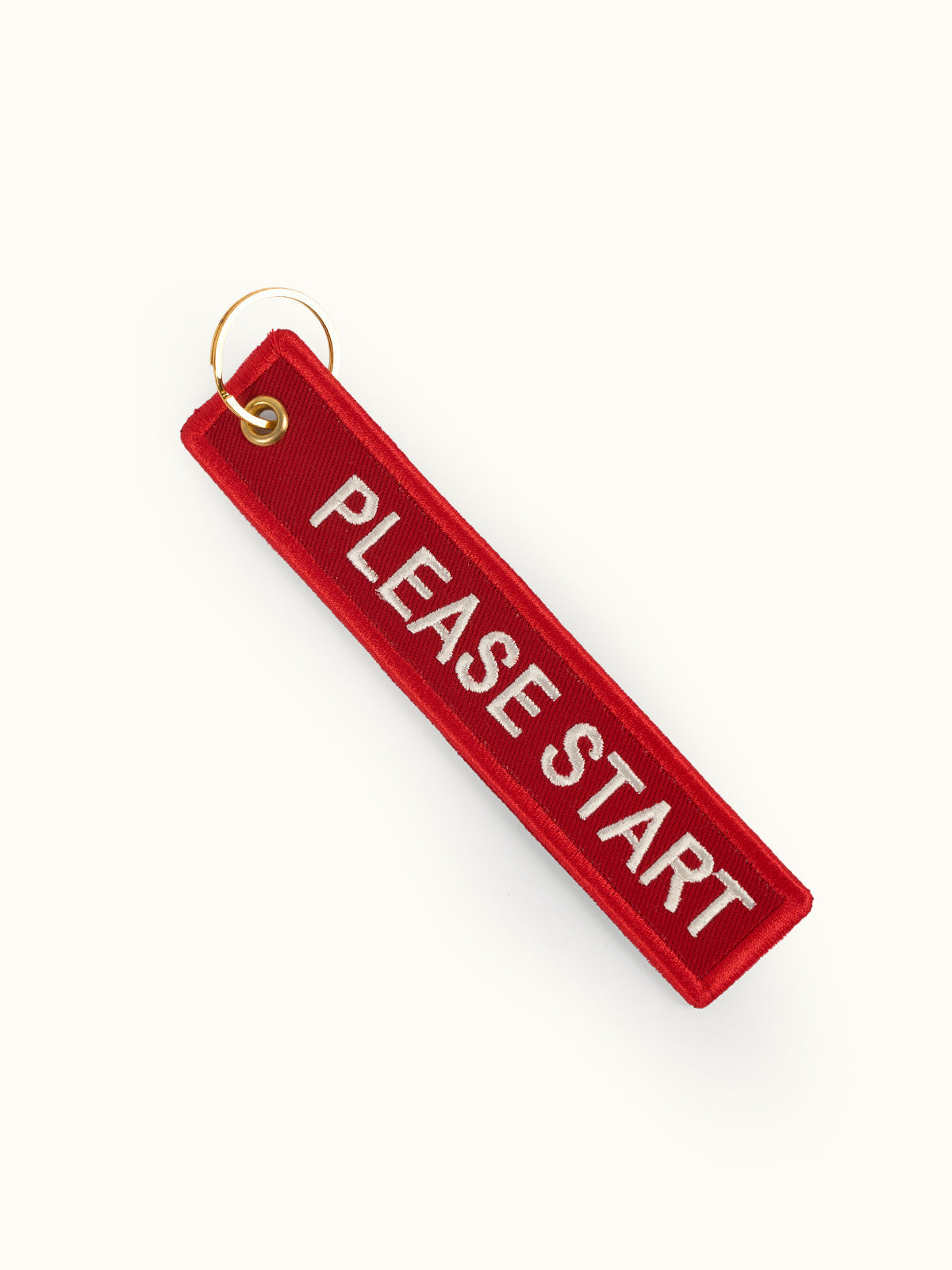 Llavero Please Start, detalle — borde merrow al tono, ojal metálico y argolla partida de 30 mm. #color_rojo