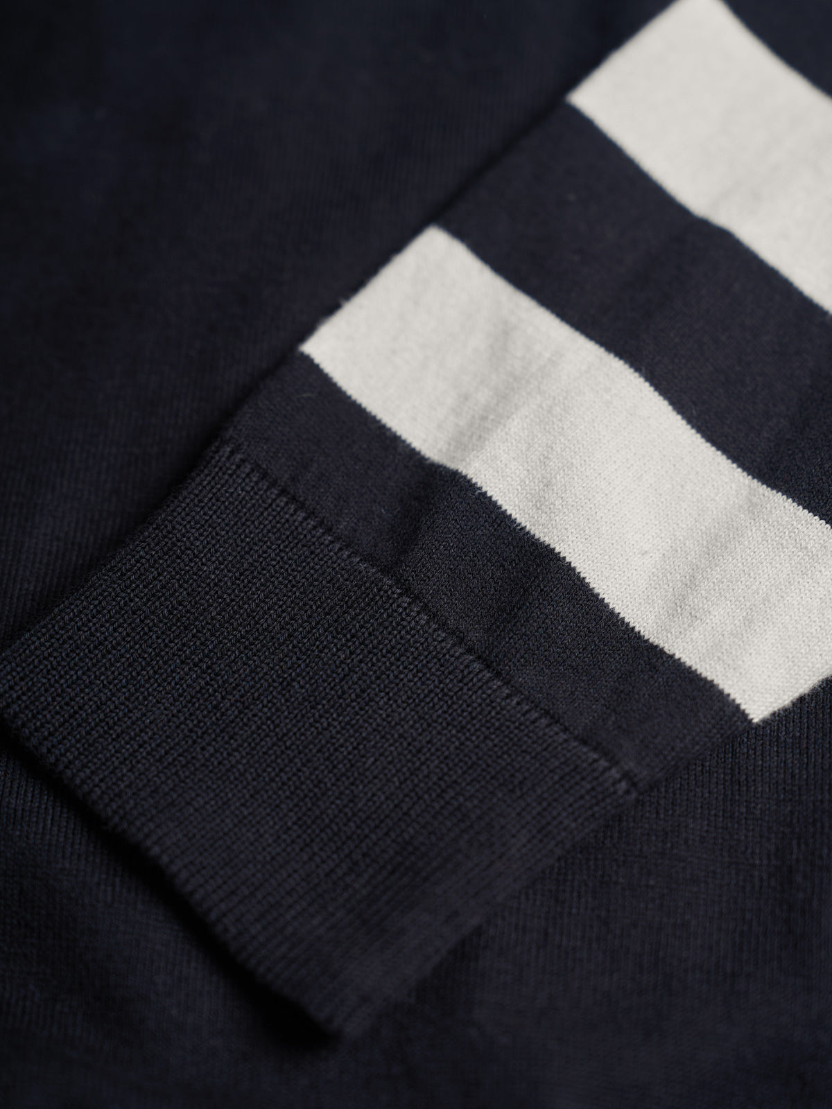 Suéter Jacquard Maine, detalle — un gráfico jacquard de gran presencia al frente y mangas a rayas a contraste. #color_negro